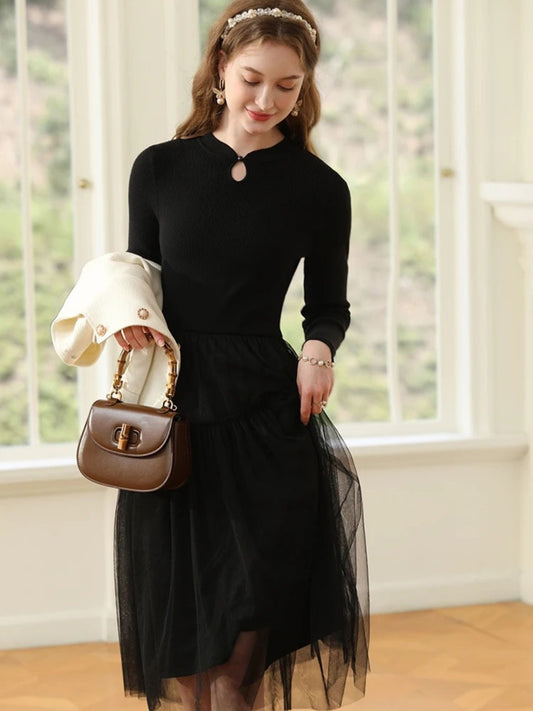 Woman walking in black tiered dress, holding a white coat and brown purse.
