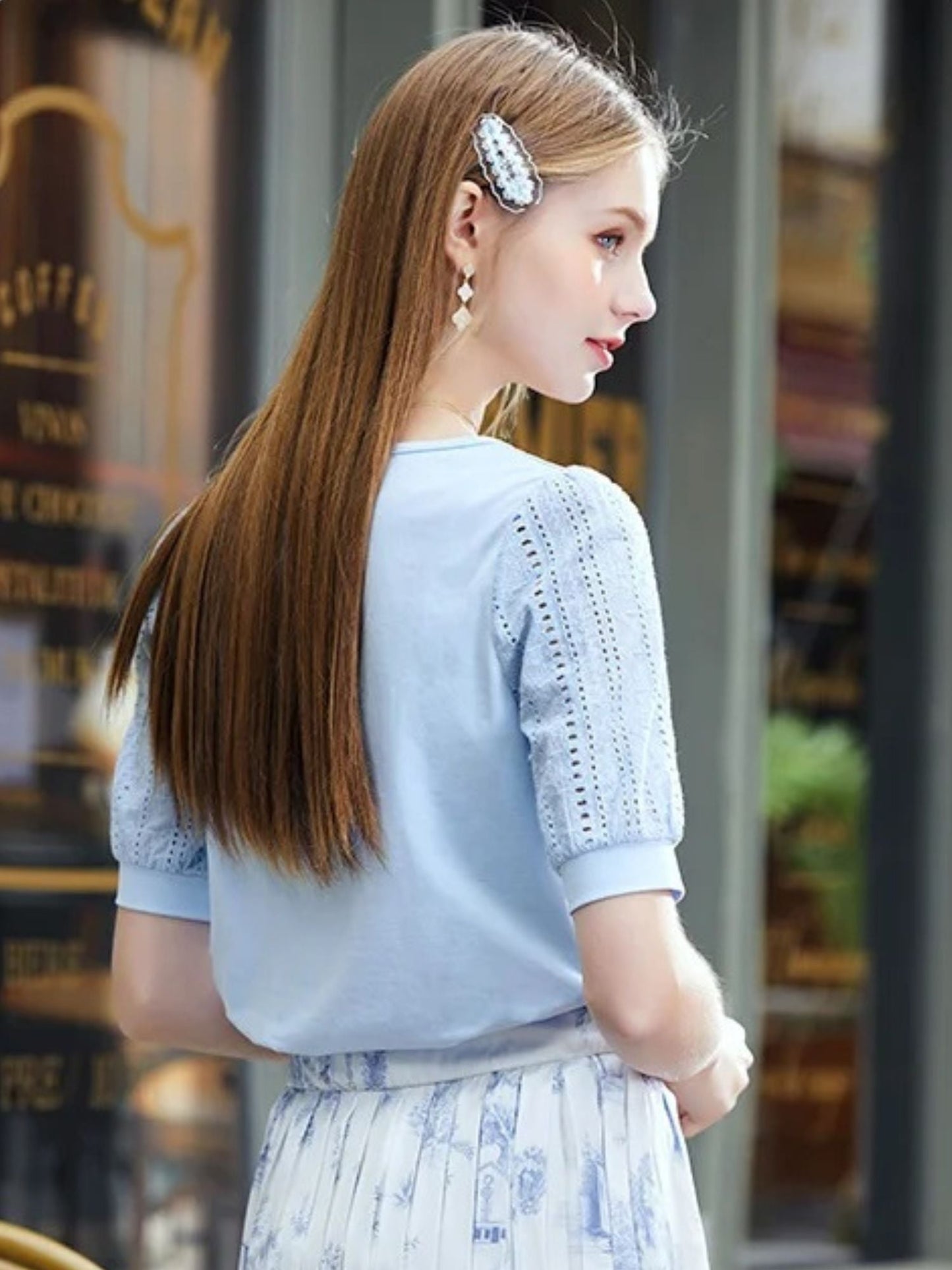 Side view of woman wearing a blue lace blouse and patterned skirt.