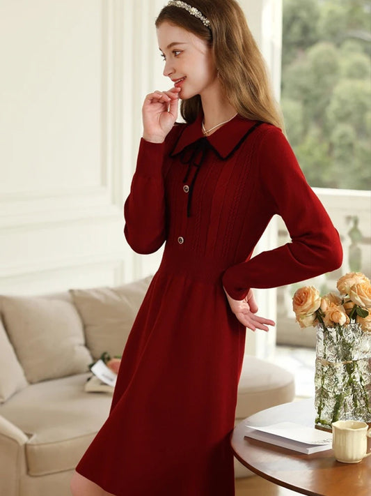 Side view of woman in red vintage dress standing near a cream sofa.