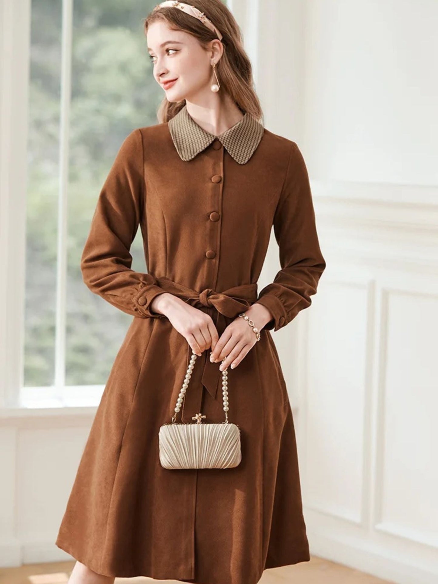 Side view of woman in brown collared dress with hands in pockets.