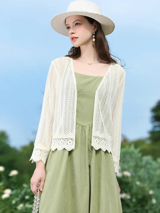 Side view of woman in open-knit cardigan and green dress, smiling under a clear sky.