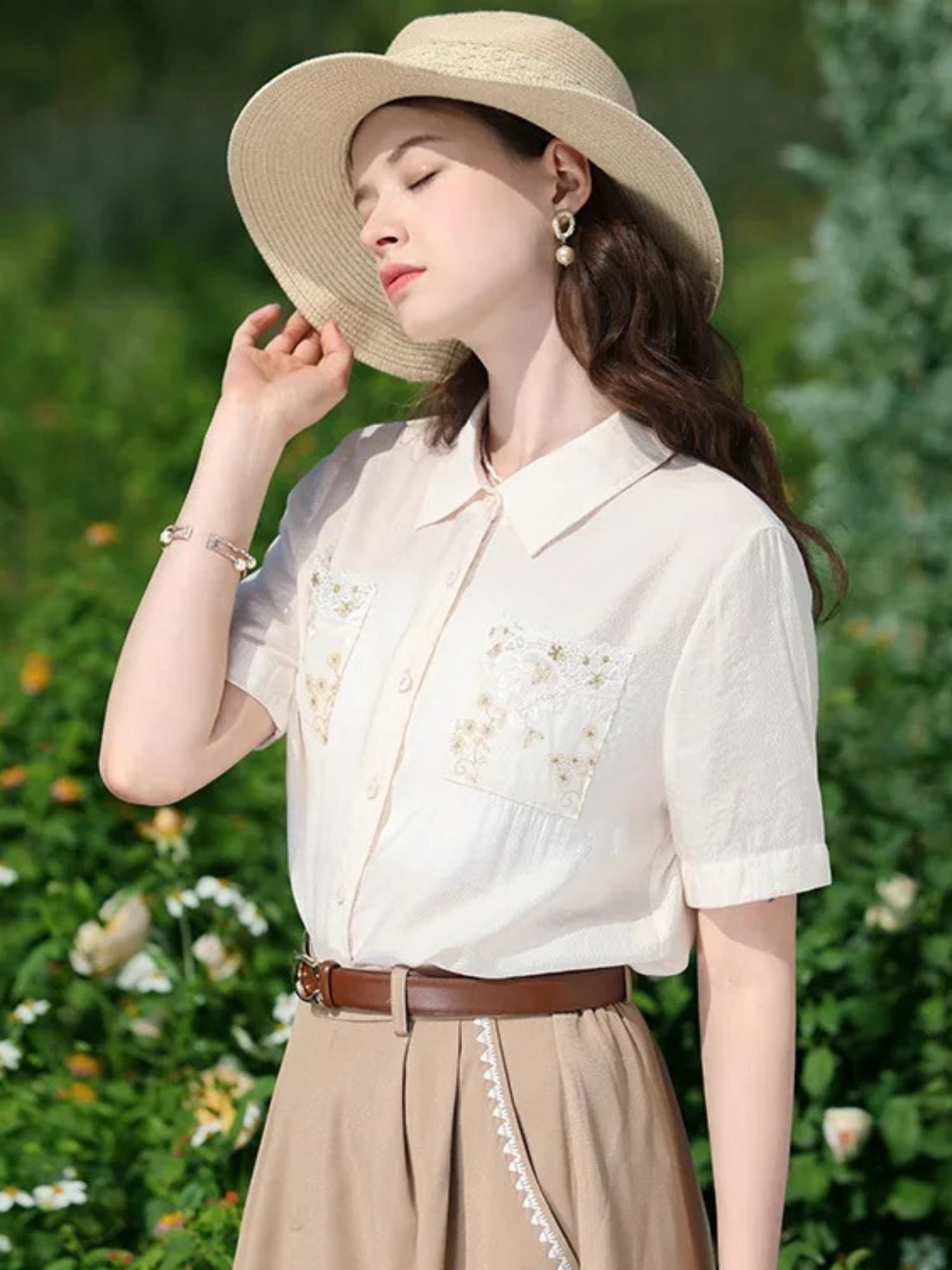 Side view of woman in white embroidered shirt and tan skirt, gazing upward.