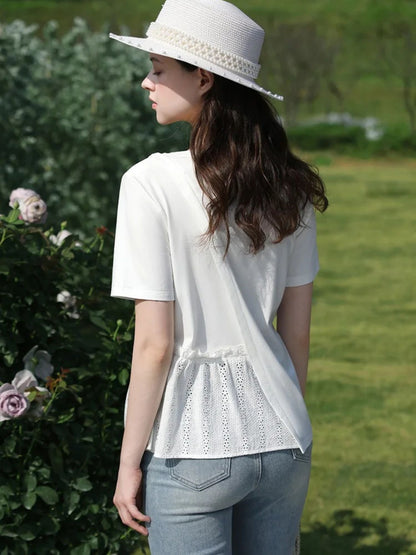 Back view of woman in lace-trimmed blouse and hat, walking beside flowering bushes.
