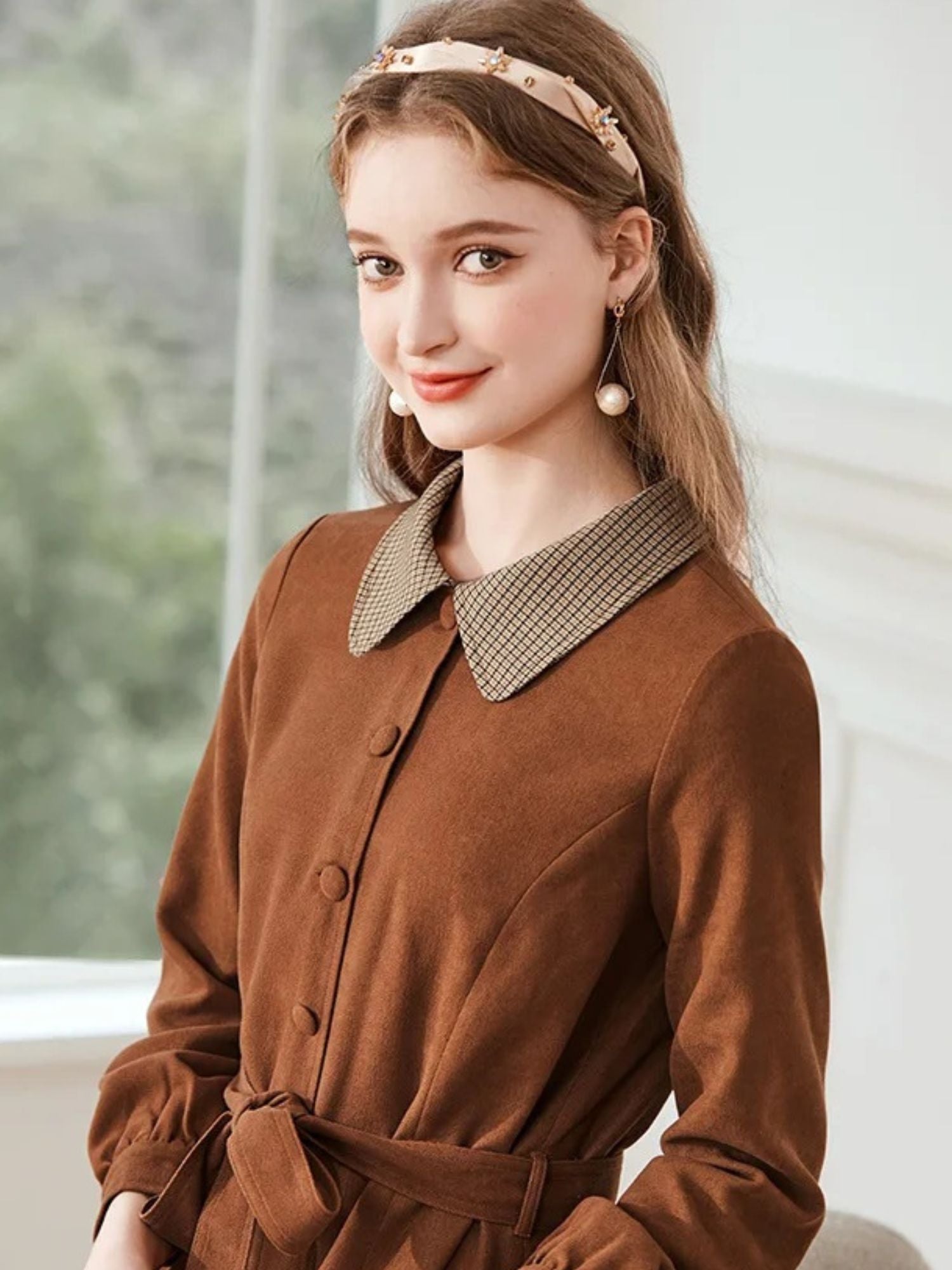 Close-up of woman in brown dress with houndstooth collar and tie waist.