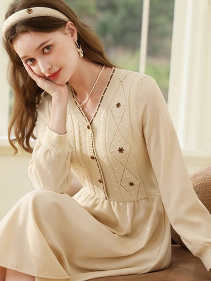 Woman sitting in cream dress, lifting the hem slightly to cross her legs.
