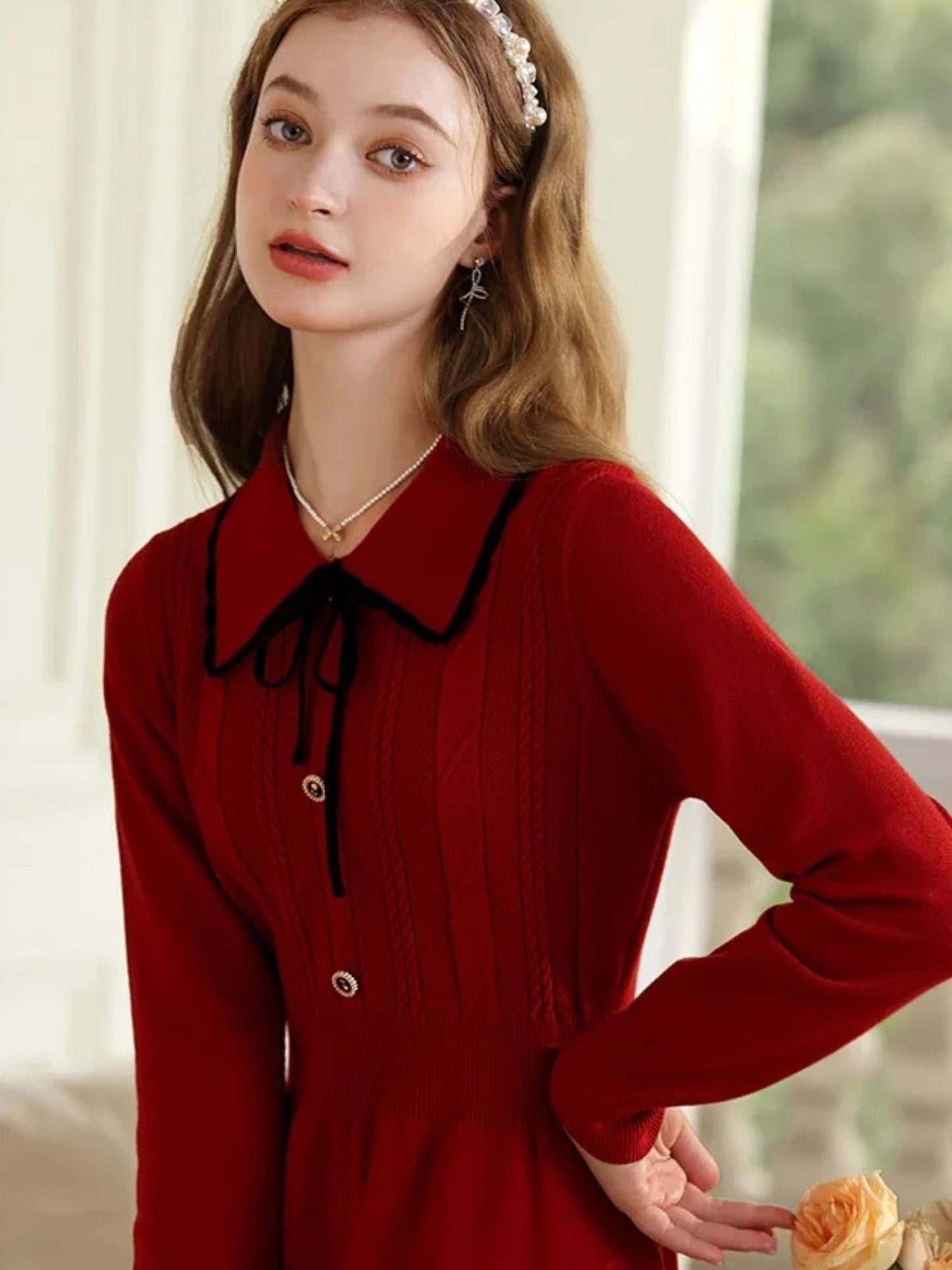 Close-up of woman in red dress with hands on hips, showing collar detail.