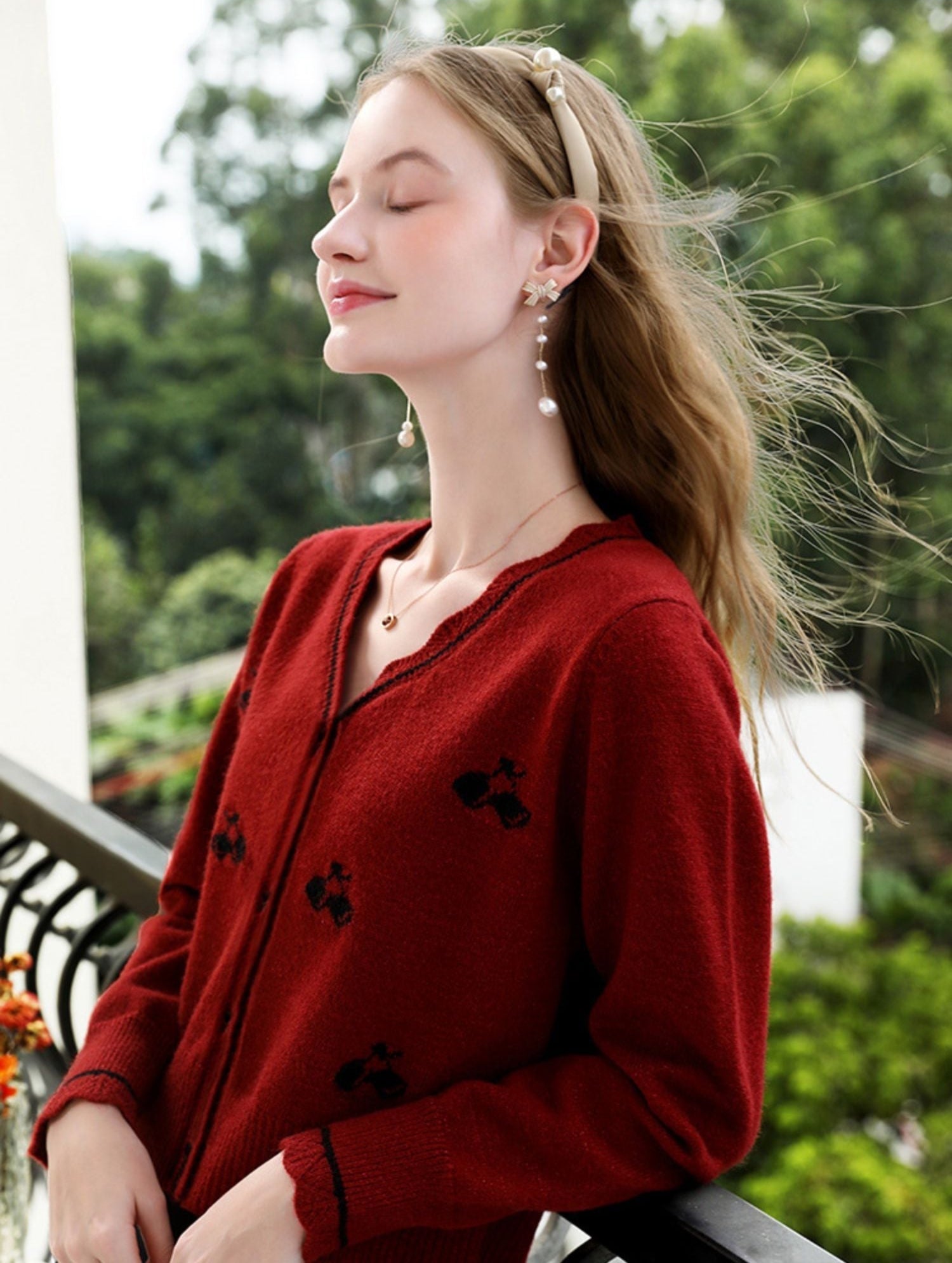 Side view of woman in floral knit cardigan gazing out from a balcony.