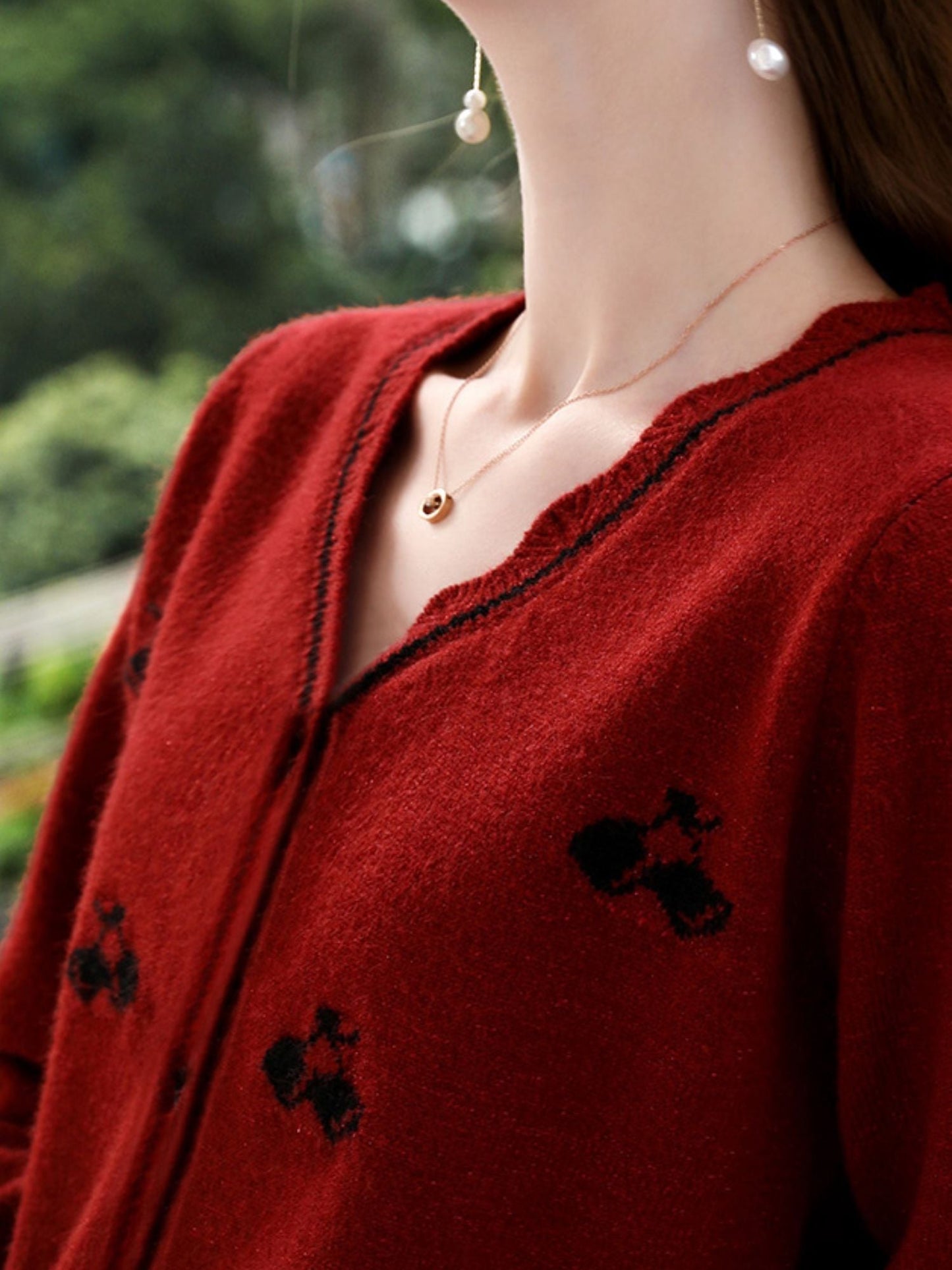 Close-up of red cardigan fabric showing dark floral embroidery and V-neckline.
