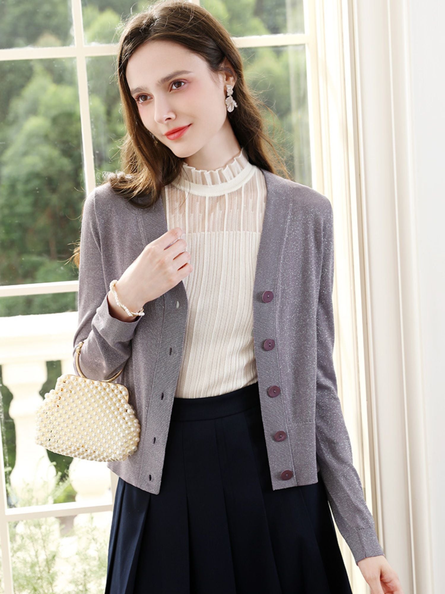 Woman adjusting lavender knit cardigan over blouse with decorative collar and navy skirt.
